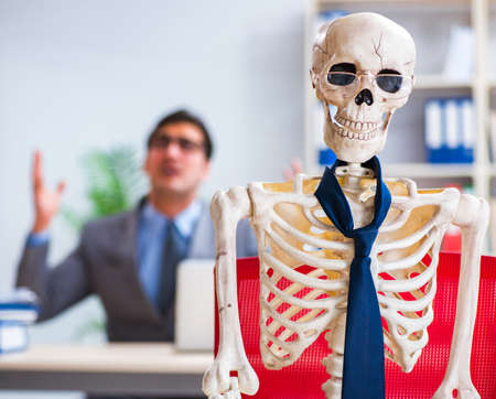 Businessman working with skeleton in officeの写真素材