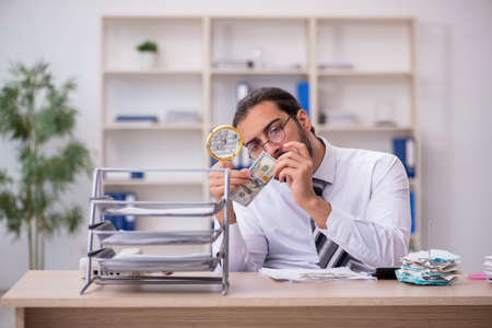Young male bookkeeper in counterfeit bills conceptの写真素材
