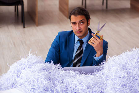 Young male employee and a lot of cut papers in the officeの写真素材