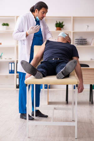 Old man visiting young doctor in vaccination conceptの写真素材
