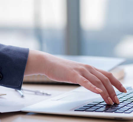 Female finance professional working on keyboard with reports