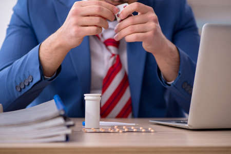 Young male employee suffering at workplaceの写真素材