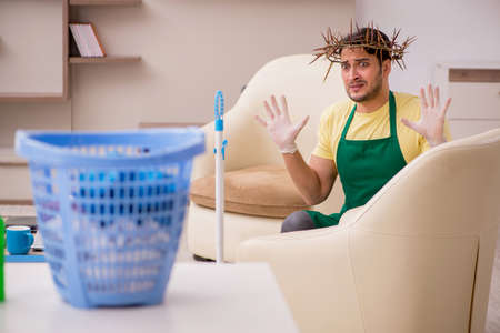 Young male contractor wearing prickly wreath on head cleaning thの写真素材