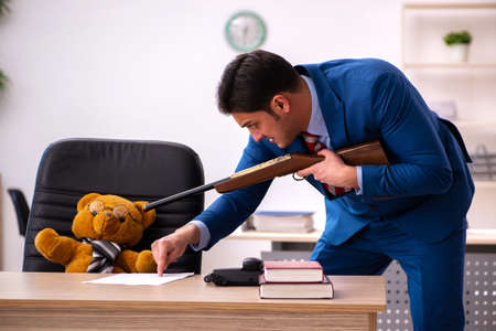 Young male employee and his toy bear boss in funny conceptの写真素材
