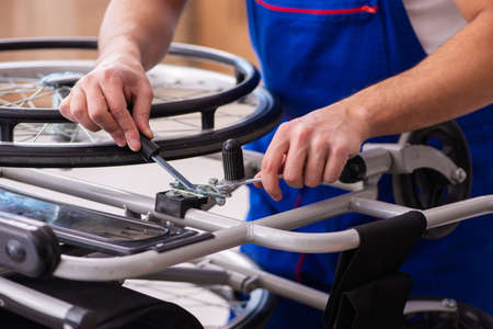 Young male repairer repairing wheel-chair indoorsの写真素材