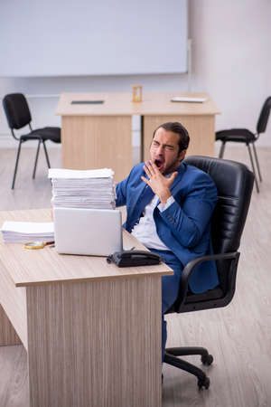 Young male employee and too much work in the officeの写真素材