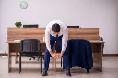 Young businessman employee doing sport exercises at workplaceの写真素材