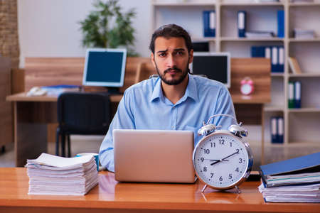 Young male employee in time management conceptの写真素材