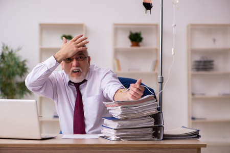 Old male employee in blood transfusion conceptの写真素材