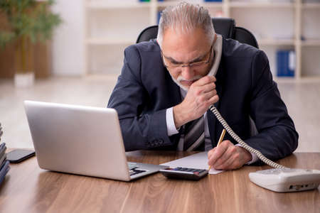 Aged male employee unhappy with excessive work in the officeの写真素材