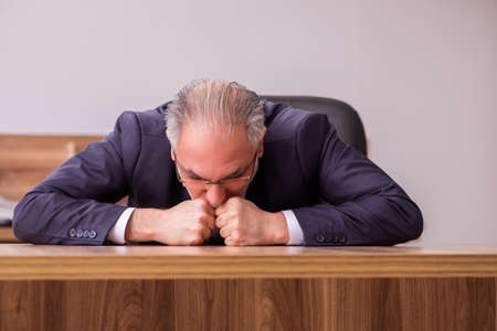 Old businessman employee sitting in the officeの写真素材