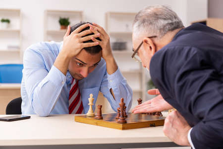 Two businessmen playing chess in the office