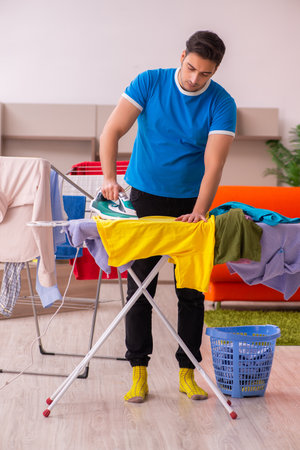 Young man husband doing ironing at homeの写真素材
