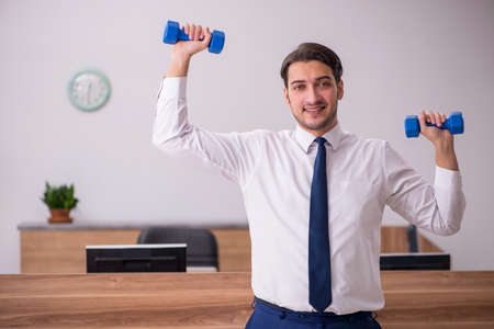 Young businessman employee doing sport exercises at workplaceの写真素材