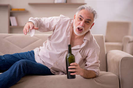 Old man drinking alcohol at homeの写真素材