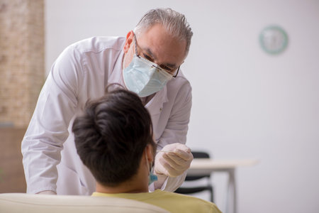 Young male patient visiting old male doctor otorhinolaryngologisの写真素材