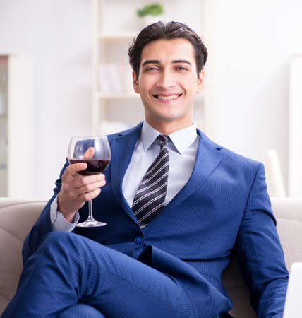 Businessman drinking wine sitting at homeの写真素材