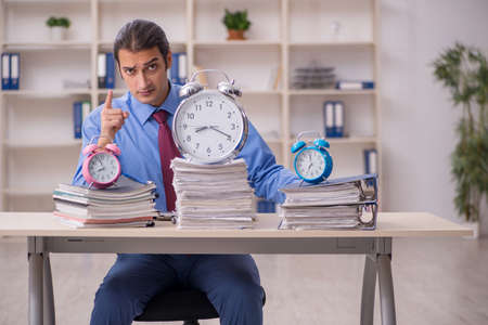 Young male employee in time management conceptの写真素材