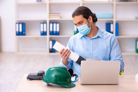 Young male architect working in the office during pandemic
