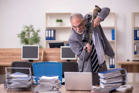 Old male employee unhappy with excessive work in the officeの写真素材