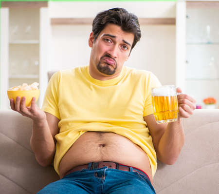 Fat obese man holding beer in dieting conceptの写真素材
