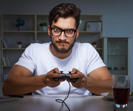 Young man playing games long hours late in the officeの写真素材