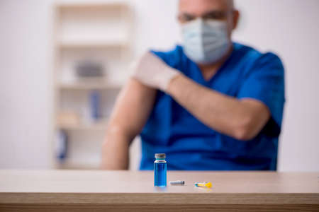 Old male doctor in vaccination conceptの写真素材