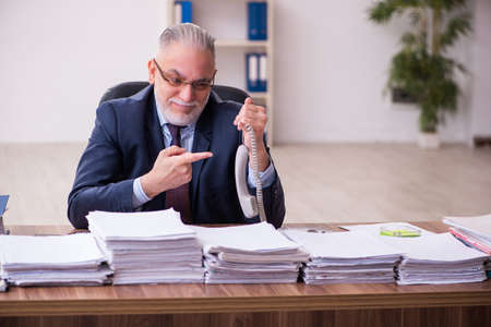 Old businessman employee unhappy with excessive work in the officeの写真素材