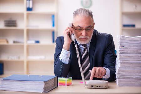 Old businessman employee unhappy with excessive work in the officeの写真素材