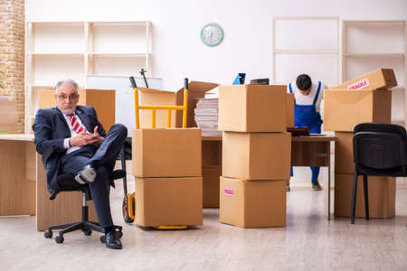 Old businessman and young contractor in relocation conceptの写真素材