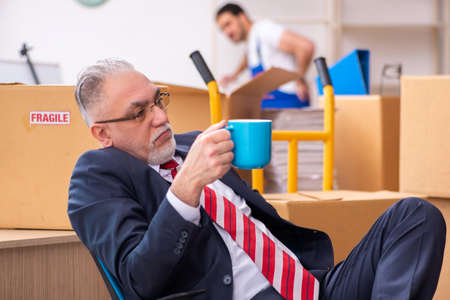 Old businessman and young contractor in relocation conceptの写真素材