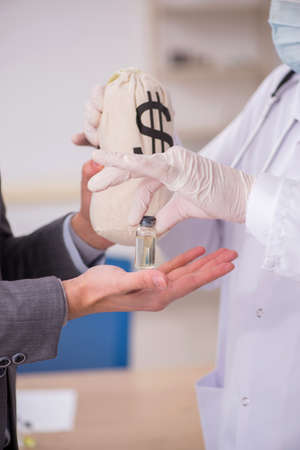 Young businessman visiting old male doctor in vaccination concepの写真素材