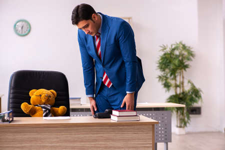 Young male employee and his toy bear boss in funny conceptの写真素材