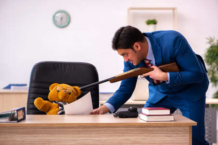 Young male employee and his toy bear boss in funny conceptの写真素材