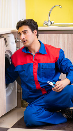 Repairman repairing washing machine in the kitchenの写真素材
