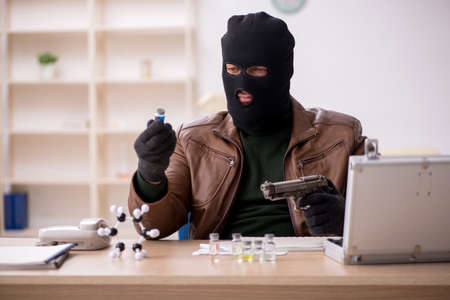 Young man in balaclava stealing vaccine from the labの写真素材