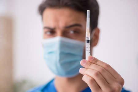 Young male doctor in vaccination concept during pandemicの写真素材