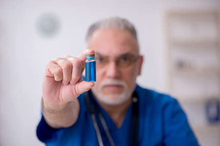 Old male doctor in vaccination concept