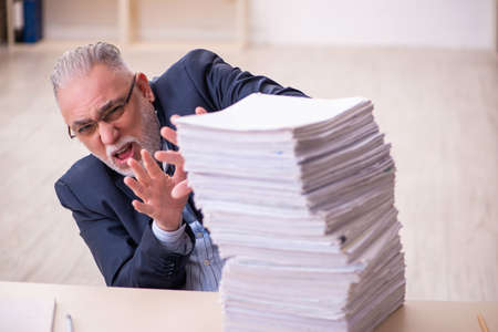 Old businessman employee unhappy with excessive work in the officeの写真素材