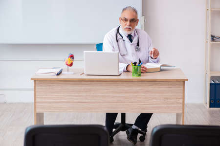 Old male doctor lecturer in the classroom during pandemicの写真素材