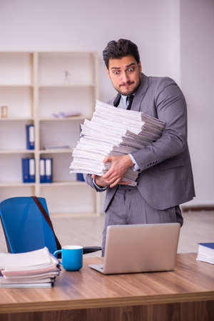 Young businessman employee unhappy with excessive work in the officeの写真素材