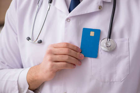 Male doctor holding credit cardの写真素材