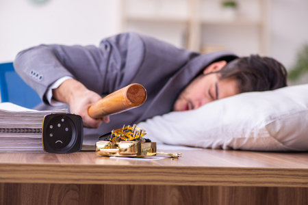Young male employee in oversleeping conceptの写真素材