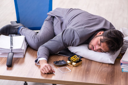 Young male employee in oversleeping conceptの写真素材