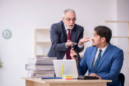 Old boss and young male employee working in the officeの写真素材