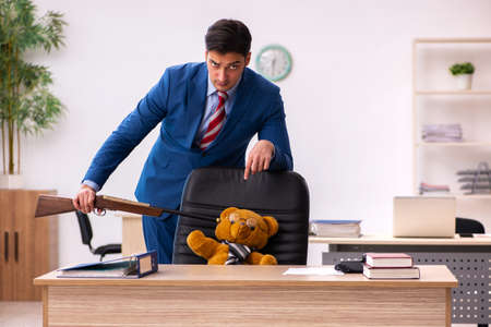Young male employee and his toy bear boss in funny conceptの写真素材