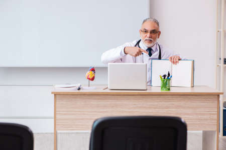 Old male doctor lecturer in the classroom during pandemicの写真素材