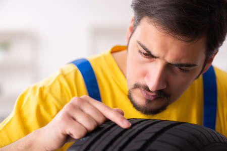 Young male garage worker with tyre at workshopの写真素材