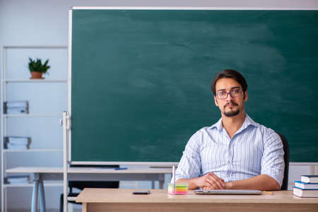 Young male teacher in front of blackboardの写真素材