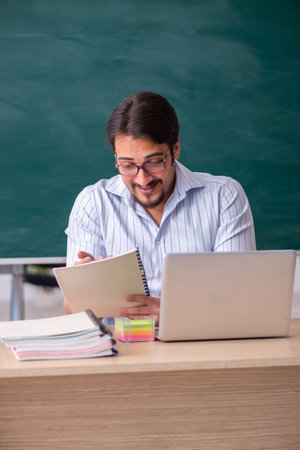 Young male teacher in front of blackboardの写真素材
